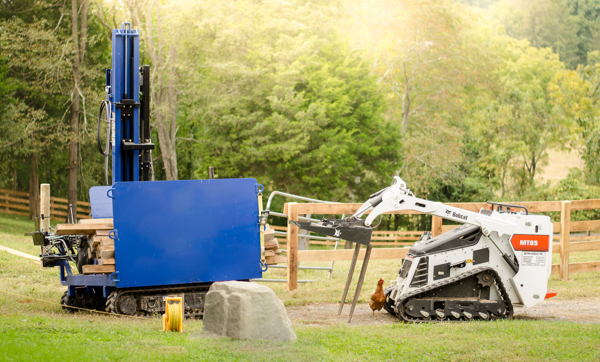A skid steer working on a fence installation on a farm