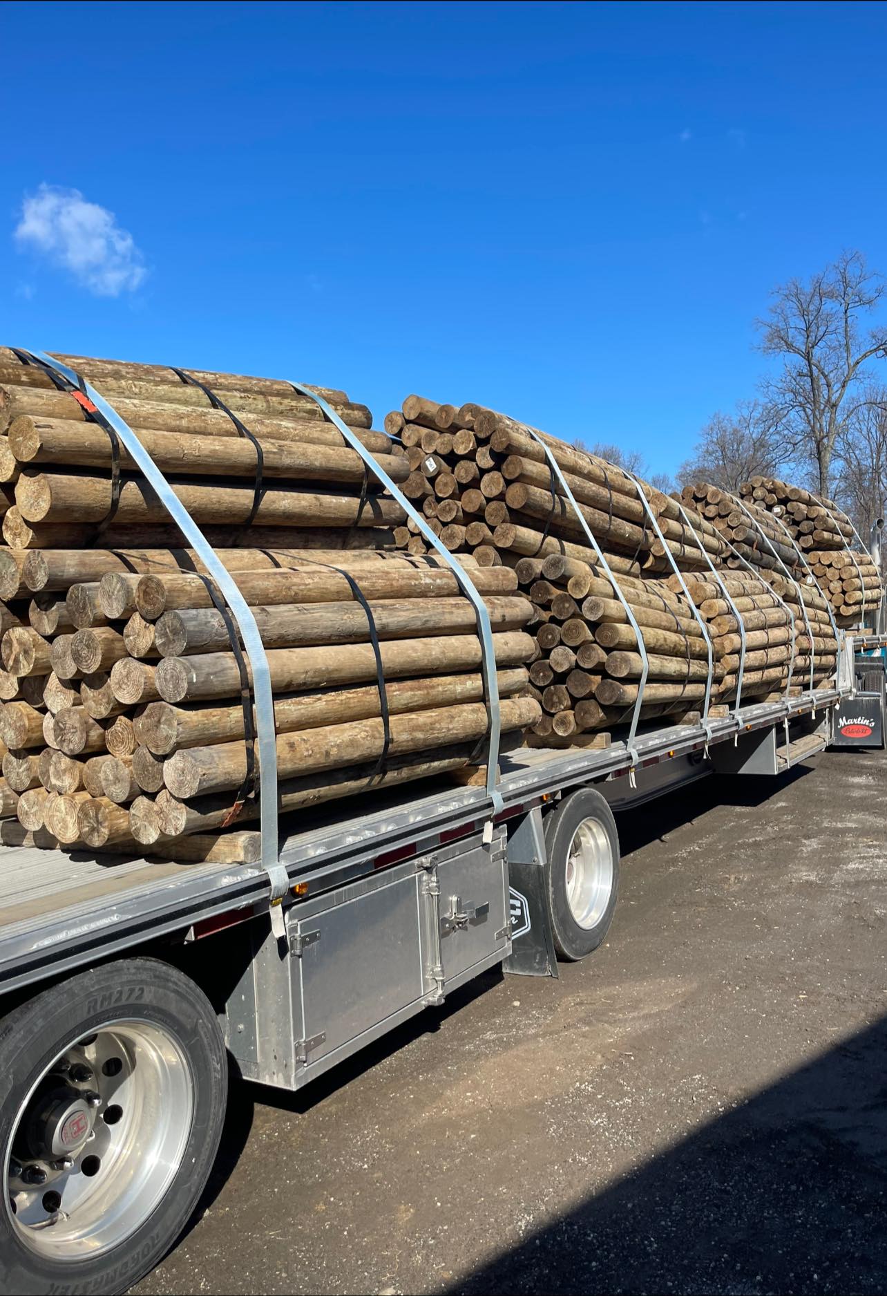 A large truck hauling freshly cut lumber for fencing